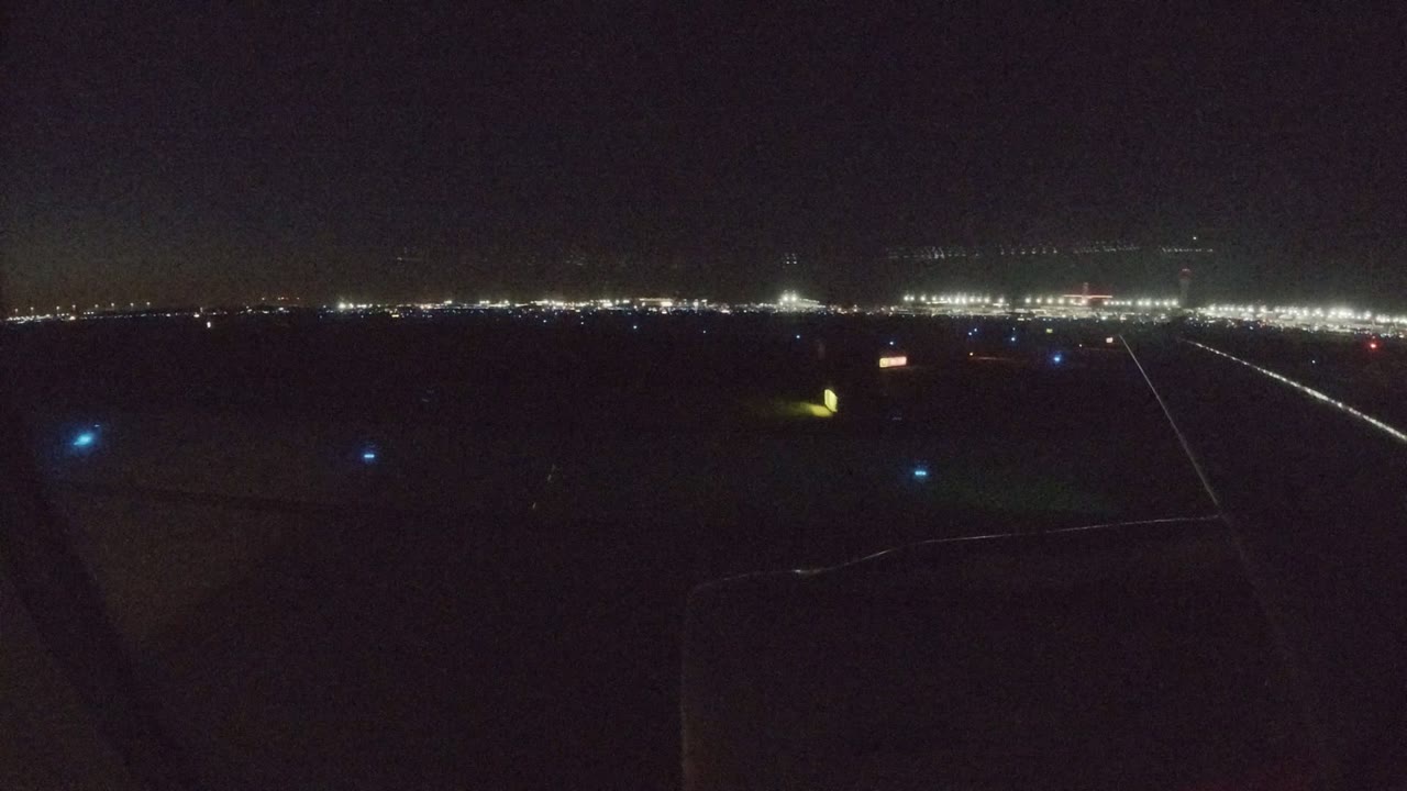 Dark airplane window view over runway lights at night.