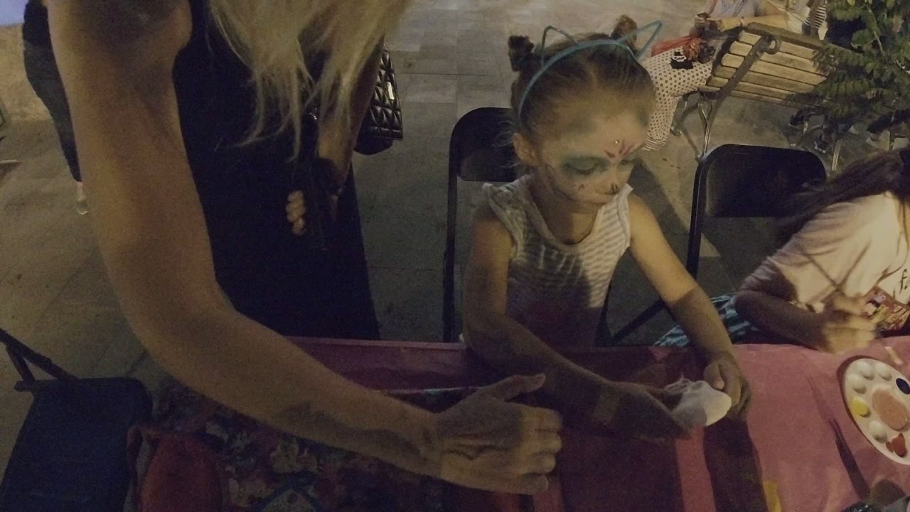 Child with face paint at a pink craft table