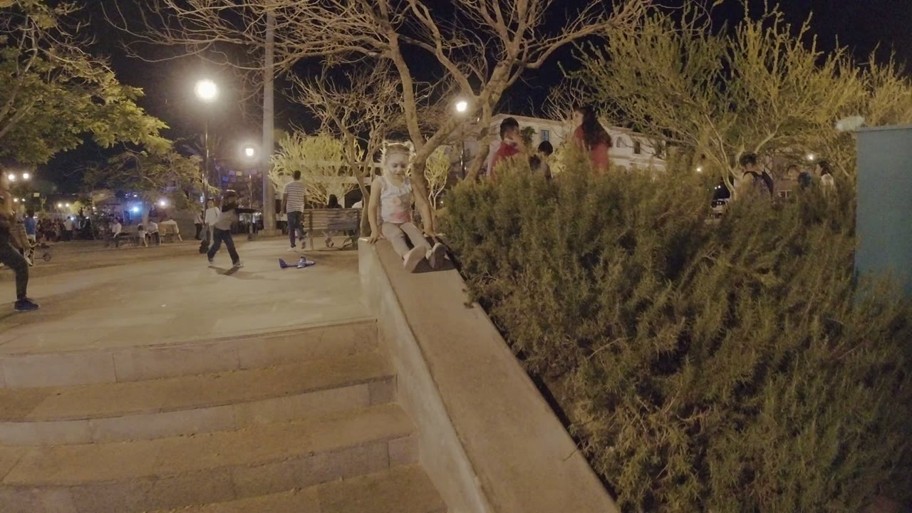 Young girl sitting on a stair handrail at night.