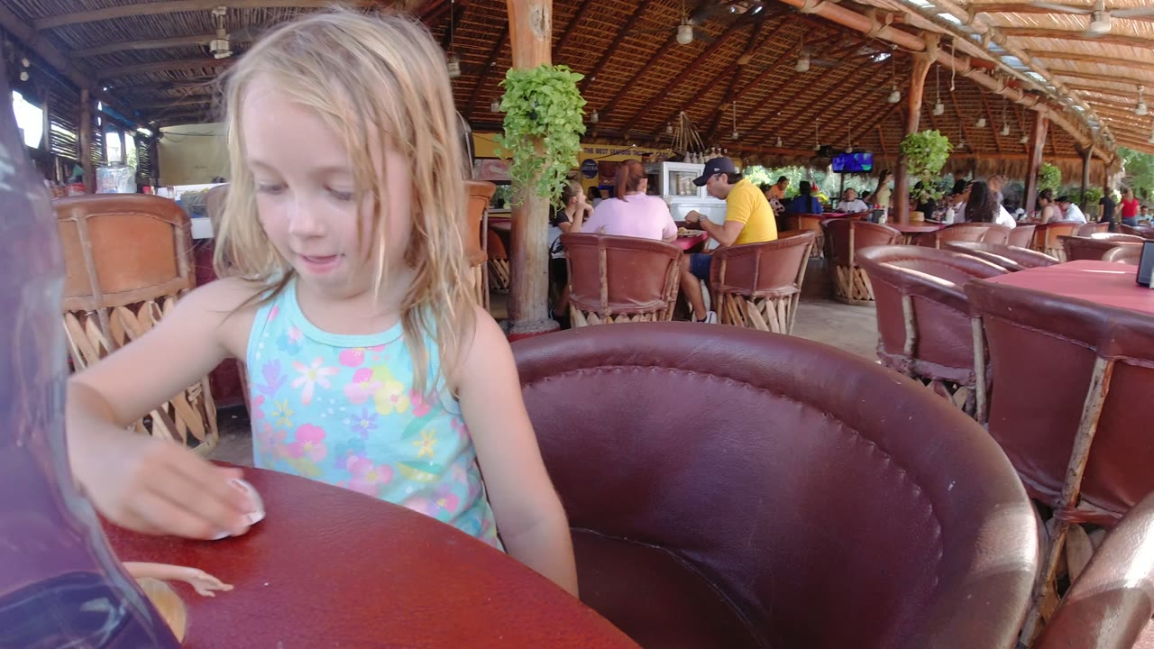 Young child wipes or plays at a red restaurant table.