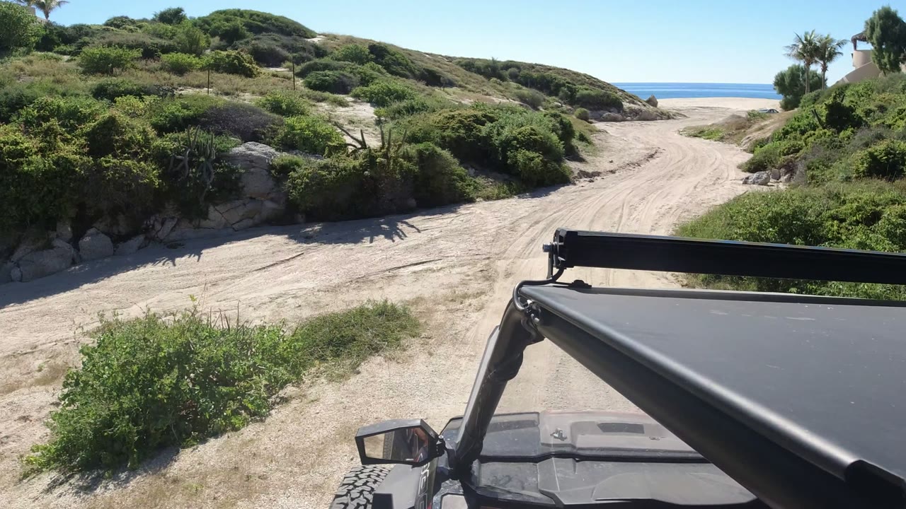 Jeep foreground on sandy coastal track leading toward ocean