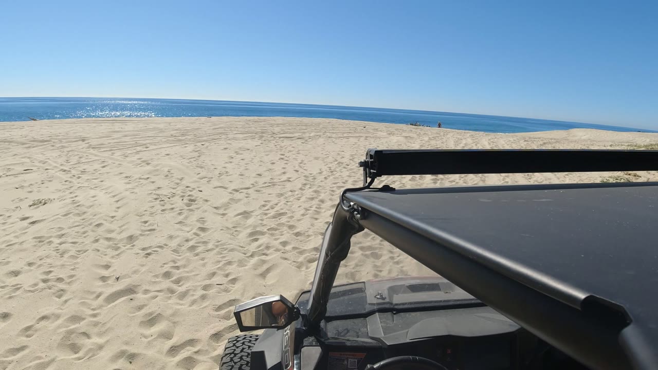 Off-road vehicle foreground on sandy beach facing the ocean