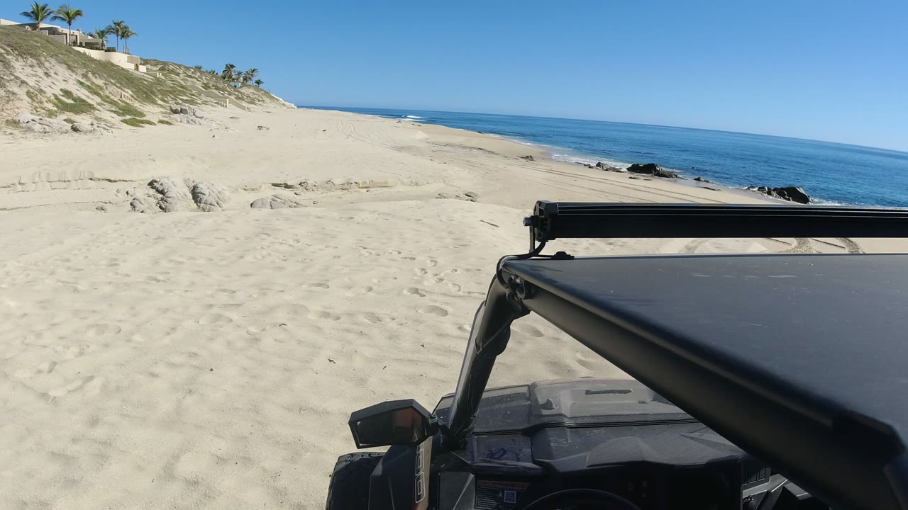 Jeep roof and light bar beside a sandy beach and blue ocean