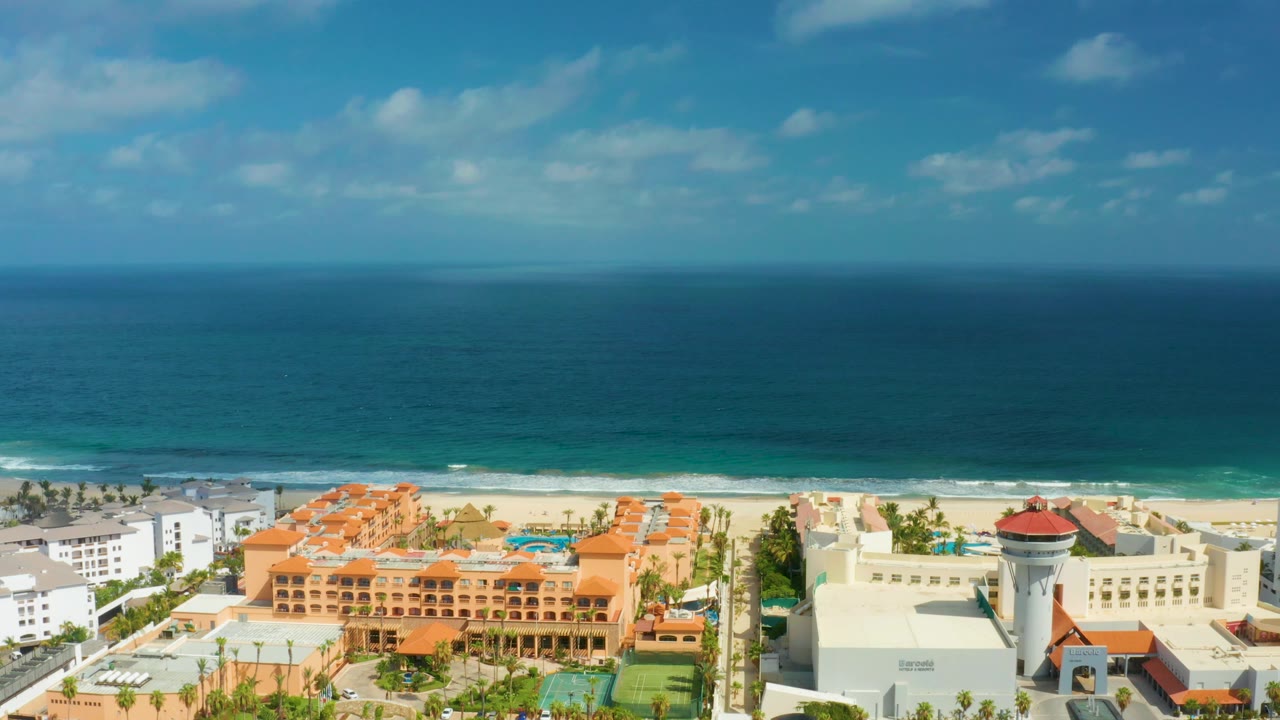 Oceanfront resort buildings with beach and waves behind them.