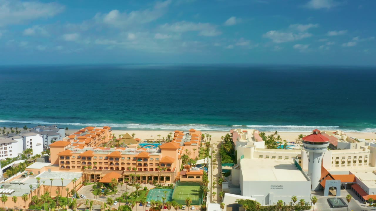 Aerial resort shoreline with orange buildings and ocean waves.