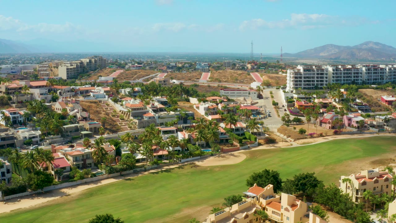 Sunlit urban area beside a golf fairway and hills
