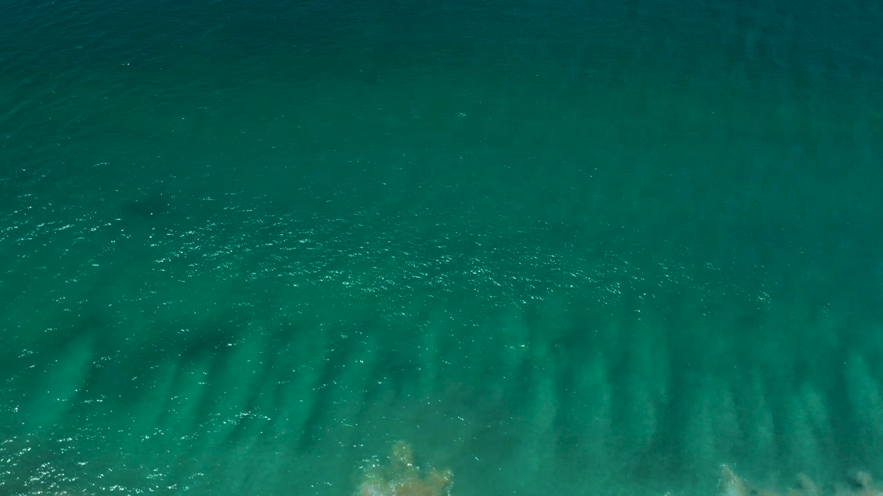 Overhead turquoise seawater with faint sandy wave patterns near the top edge.