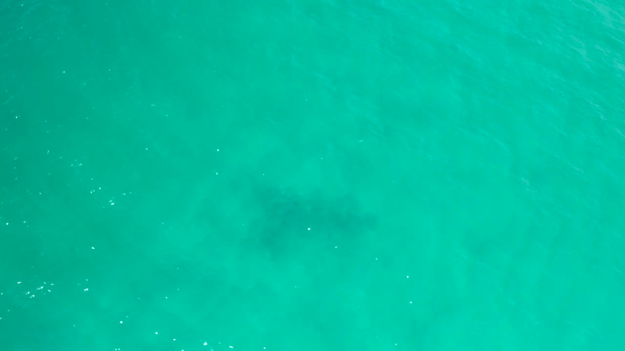Blue-green sea surface in San Jose Del Cabo, Mexico, showing scattered white flecks, soft underwater shading, and no visible people.