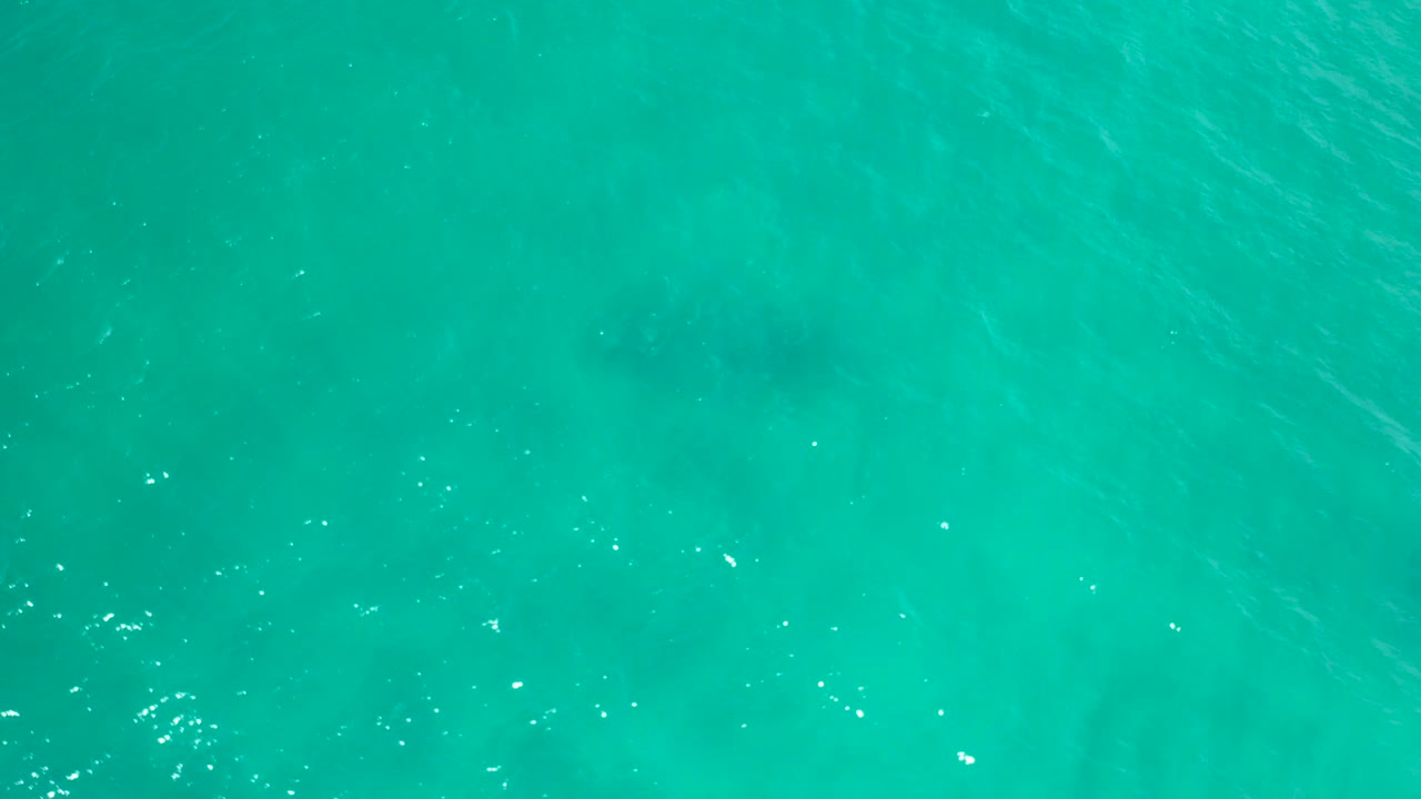 Turquoise water surface with faint darker patches below