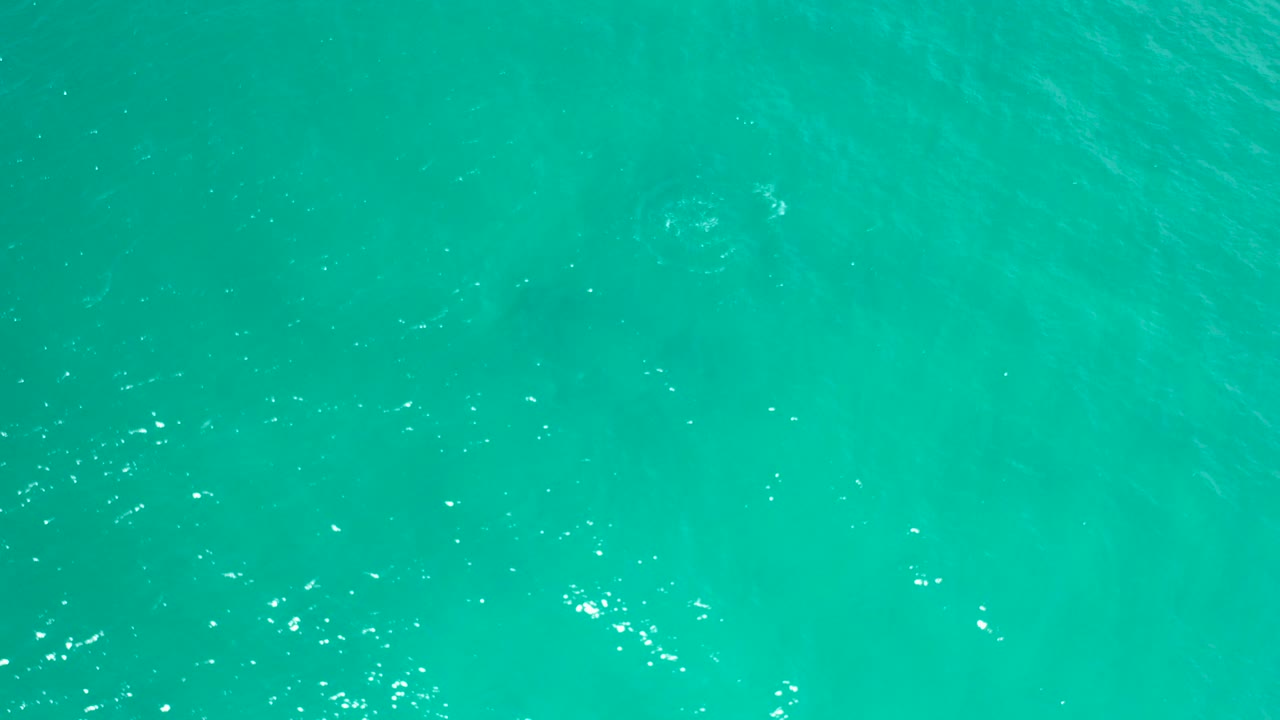 Turquoise ocean water in San Jose Del Cabo, Mexico fills the first frame with fine ripples, bright surface flecks, and no visible people.