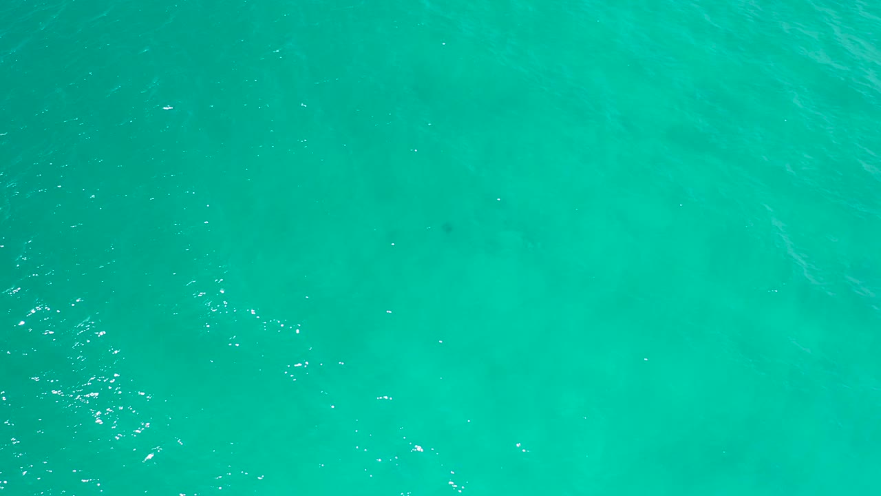 Green-blue ocean surface in San Jose Del Cabo with scattered highlights and faint darker areas under the water, no visible people.