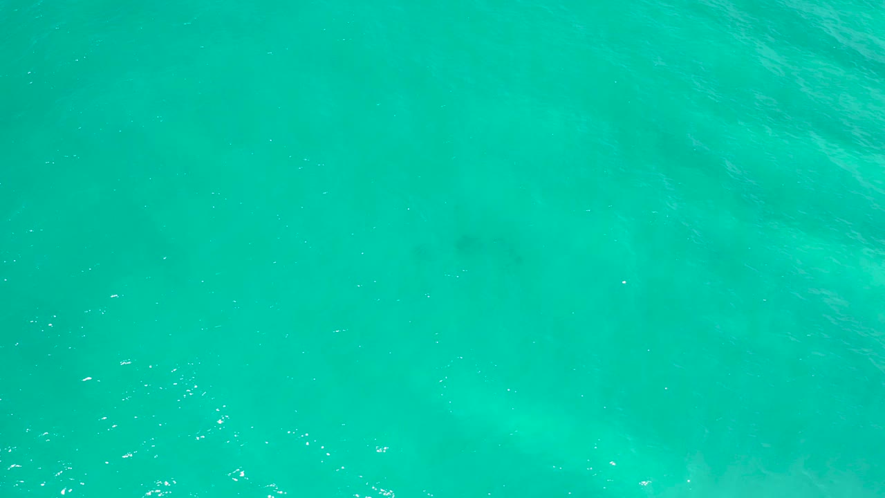 Top-down San Jose Del Cabo ocean view with turquoise water, scattered white glints on the surface, and no visible people.