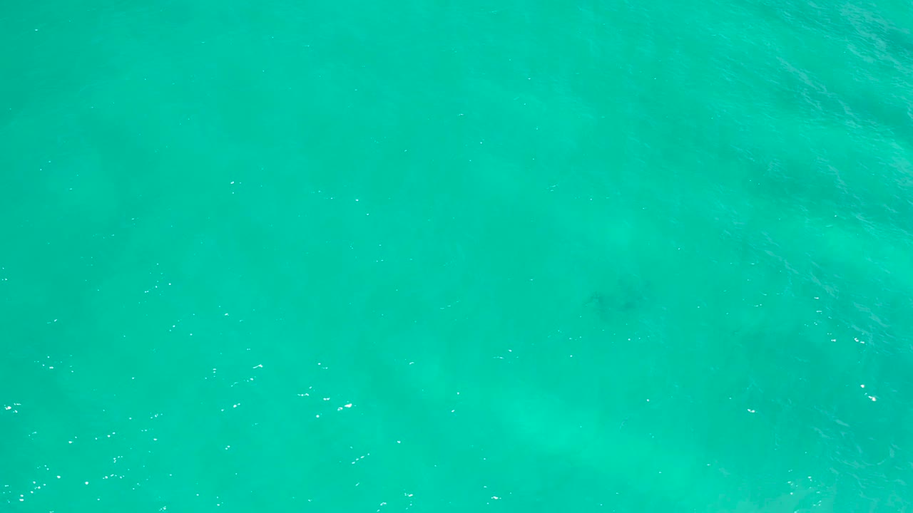 Turquoise sea surface in San Jose Del Cabo, Mexico with a darker patch low in the frame and no visible people or shoreline.