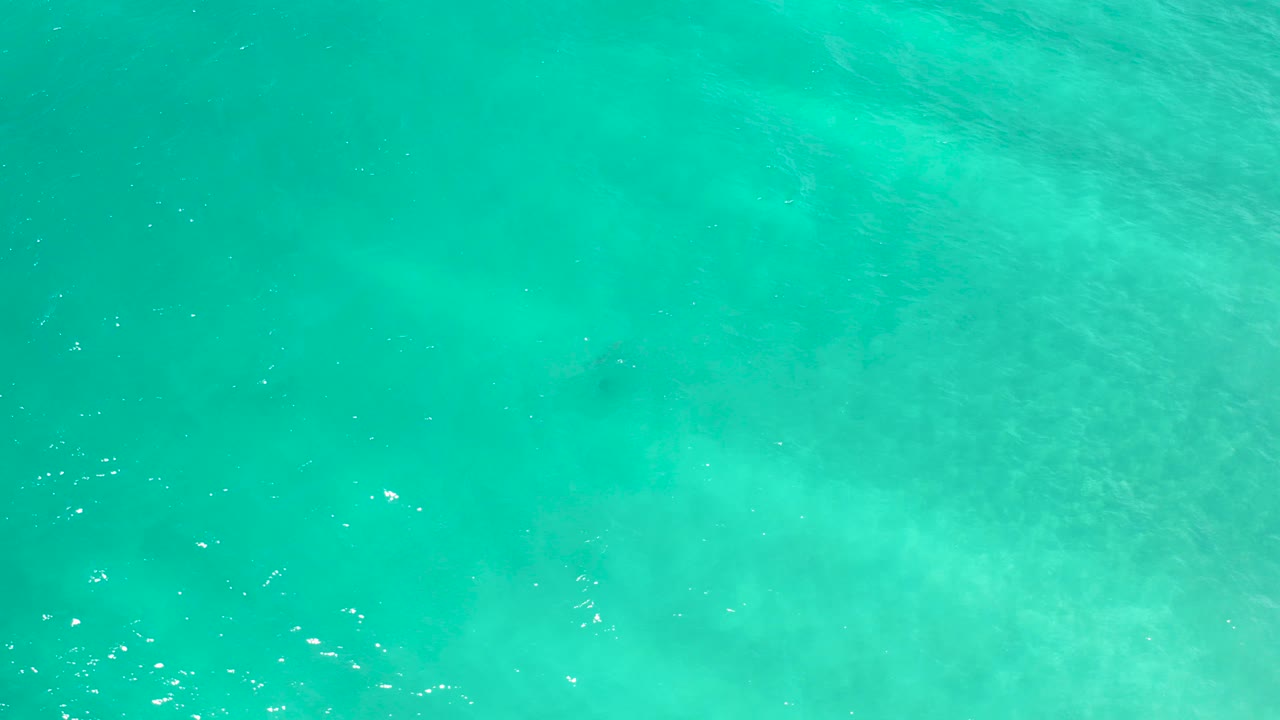Overhead view of transparent turquoise sea water in San Jose del Cabo with faint pale shallows, small surface ripples, and no visible people.