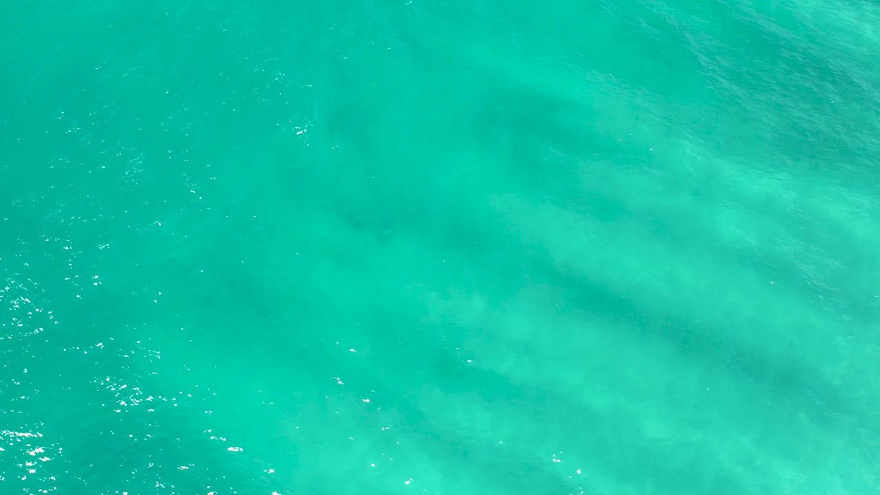 Turquoise ocean surface with pale underwater clouding.