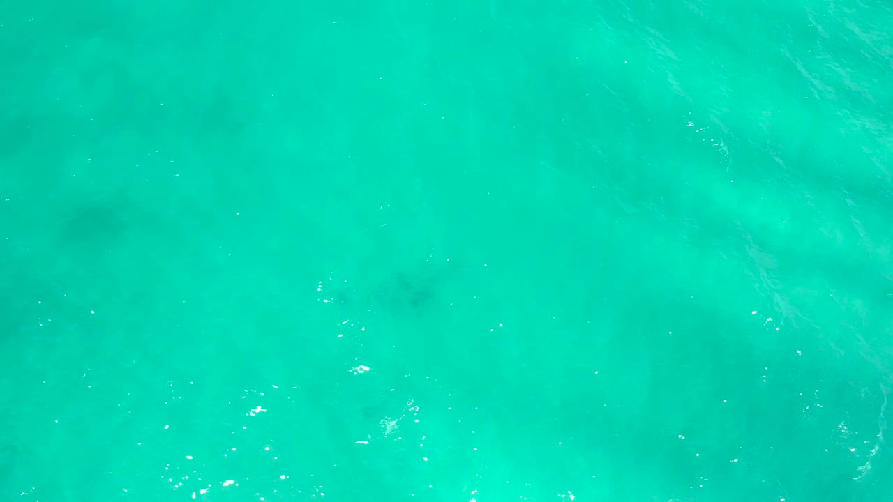Aqua ocean water in San Jose Del Cabo, Mexico, filled with diagonal ripple streaks, scattered sunlight glints, and no visible people.