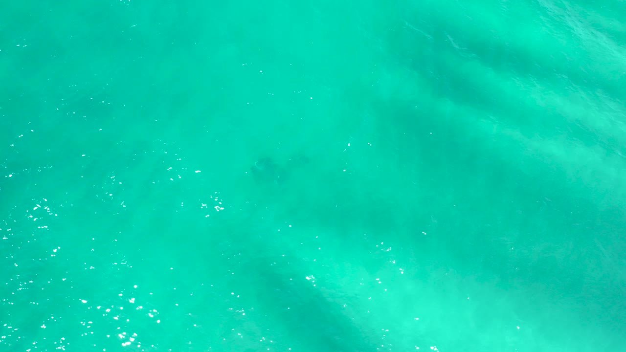 Top-down view of turquoise ocean water in San Jose del Cabo, with pale underwater sand patterns and no visible people.