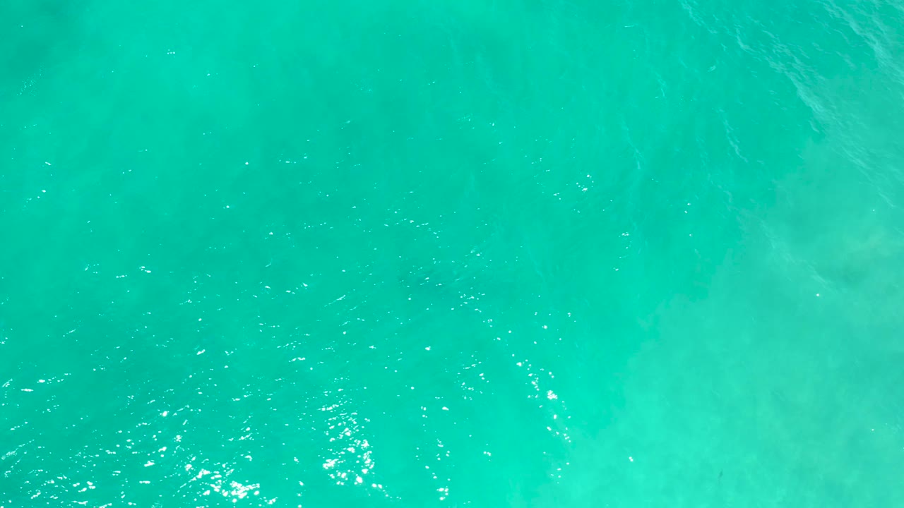 Overhead turquoise water in San Jose Del Cabo, Mexico, with darker submerged patches near the frame edge and no visible people.