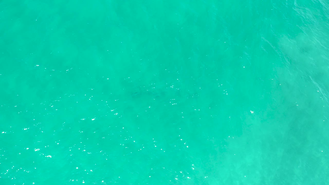 Overhead view of turquoise ocean water in San Jose Del Cabo, Mexico, with faint underwater sand patterns and no visible people.