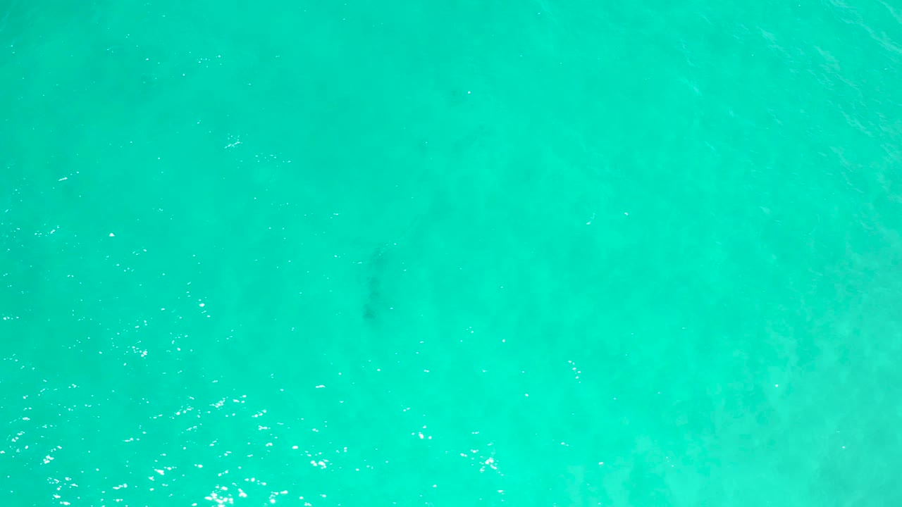 Turquoise water in San Jose Del Cabo, Mexico, seen from above with darker soft patches beneath the surface and no visible people.