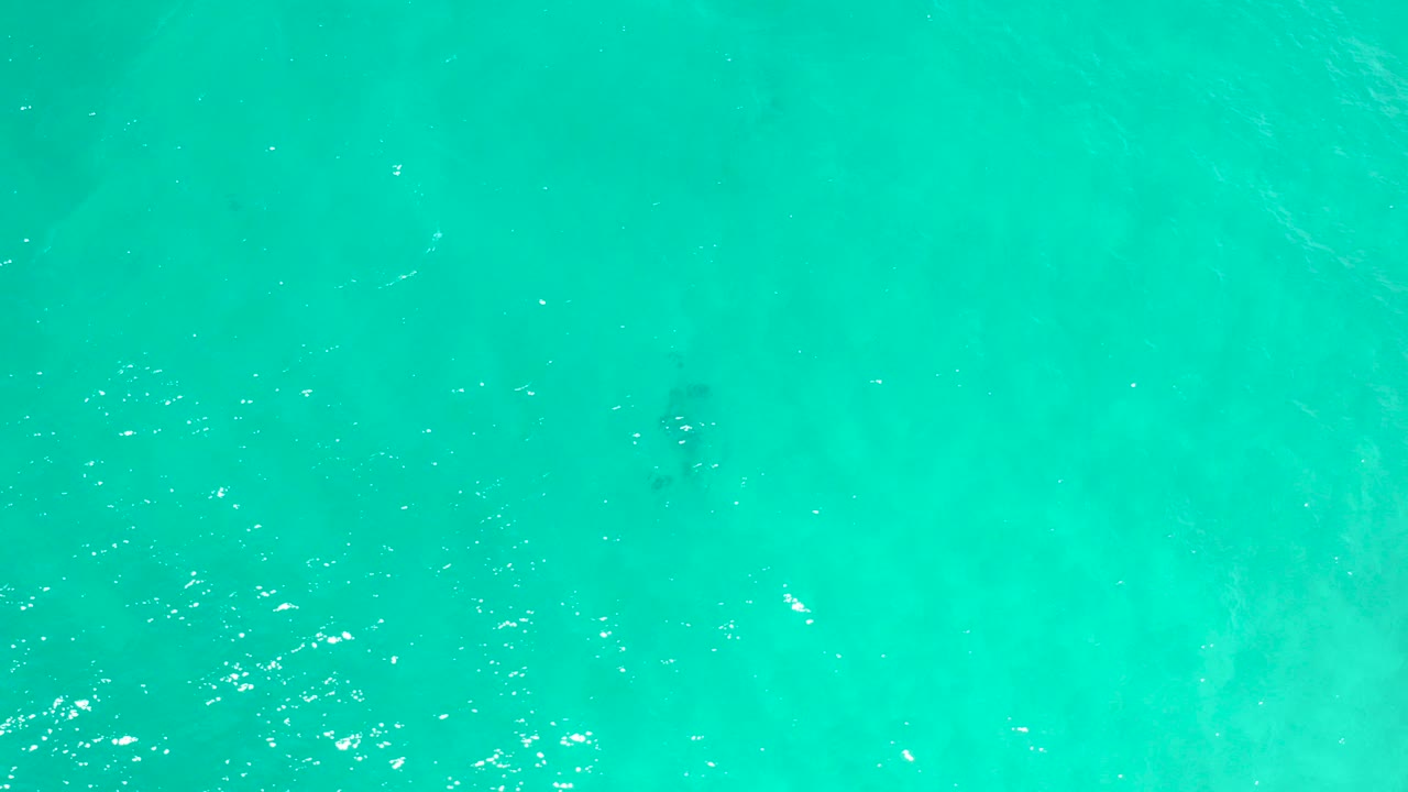 Overhead view of turquoise ocean water in San Jose Del Cabo, Mexico, with scattered bright reflections and no visible people.