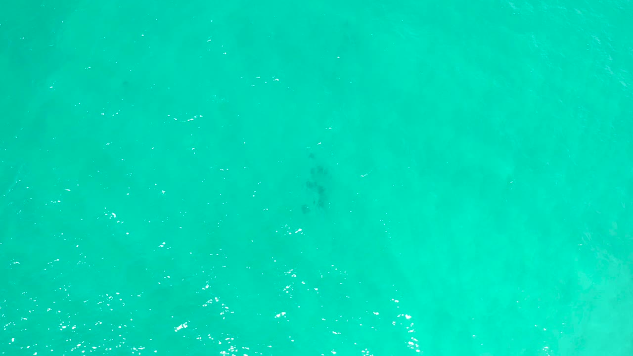 A full-frame overhead view of bright turquoise sea surface in San Jose Del Cabo, Mexico, with fine ripples, reflective specks, and no visible people.