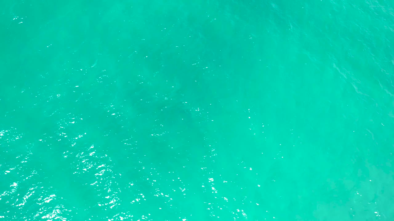 Overhead teal water in San Jose del Cabo, Mexico, with brighter broken highlights crossing the upper surface and no visible people.