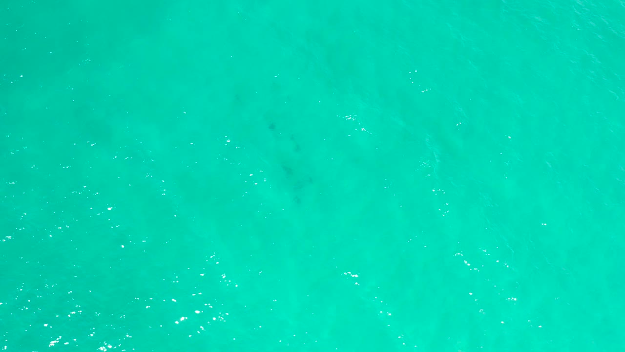 Aerial-looking view of aquamarine sea water in San Jose Del Cabo, Mexico, with small surface shimmer, slightly darker subsurface shapes, and no visible people.