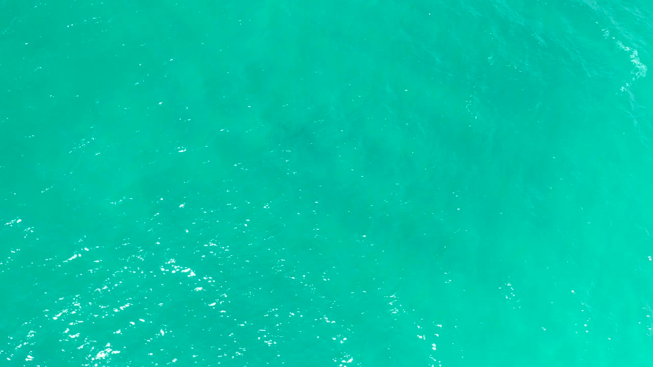 Teal water in San Jose del Cabo contains small white highlights, subtle rippled texture, a soft submerged shadow near the middle area, and no visible people.