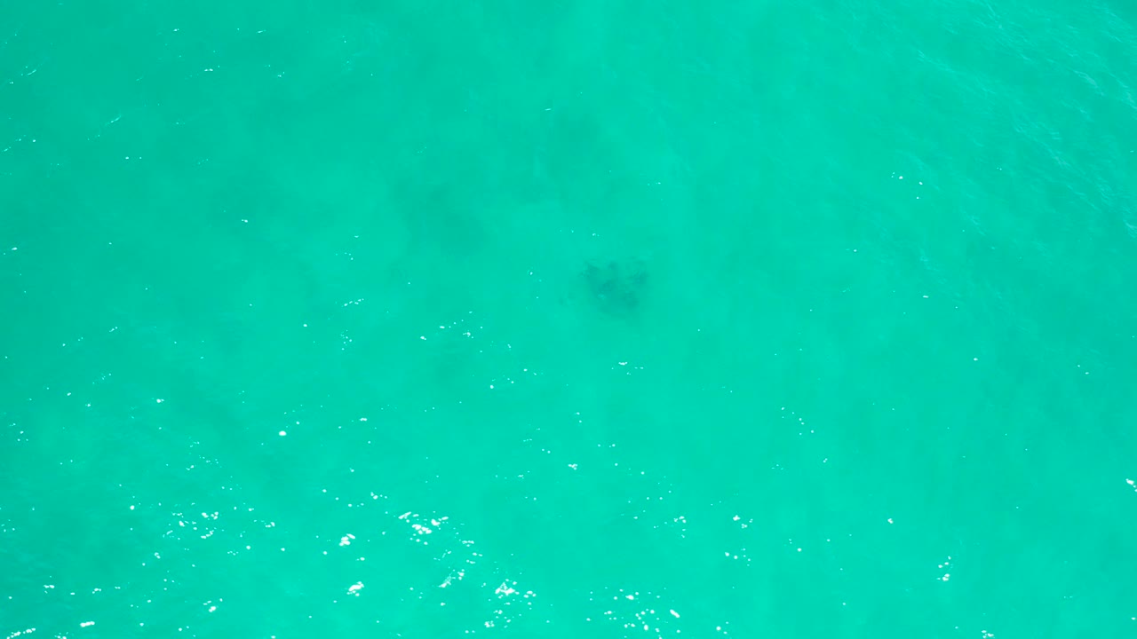 Overhead view of turquoise water in San Jose Del Cabo, Mexico, with faint darker underwater patches near the upper left and no visible people.