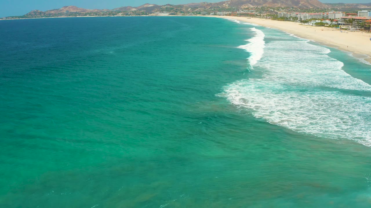 Turquoise sea with a white wave breaking beside a sandy beach