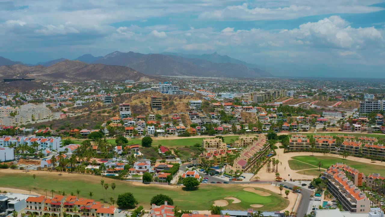Elevated view of residential blocks, golf course, roads, and mountain backdrop