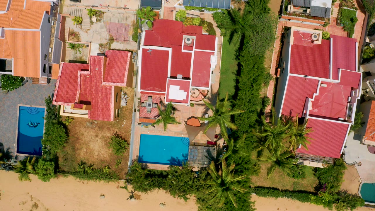 Top-down homes with red roofs, yards, and blue pools.