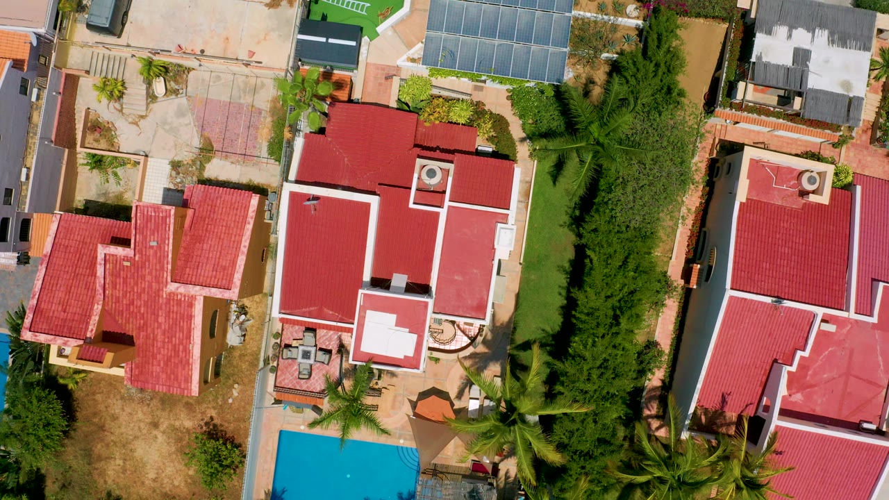 Overhead residential block with red roofs and a narrow pool view.
