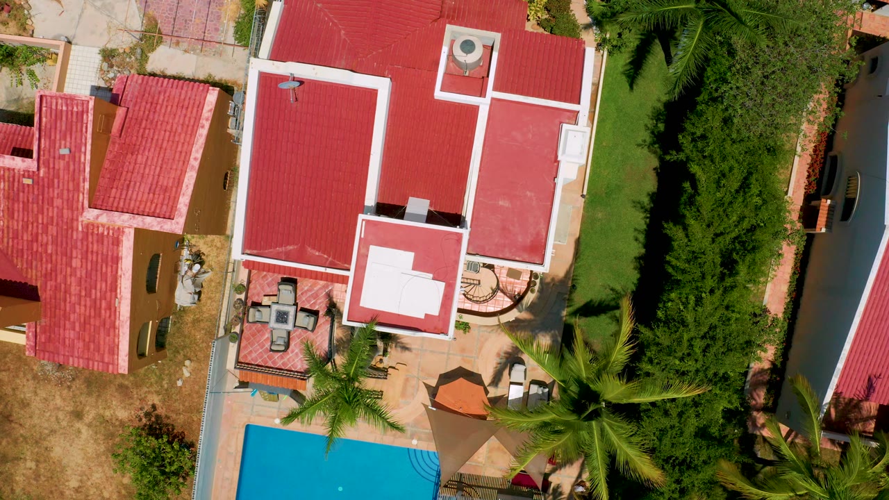 Red-roofed buildings and a pool seen from directly above.
