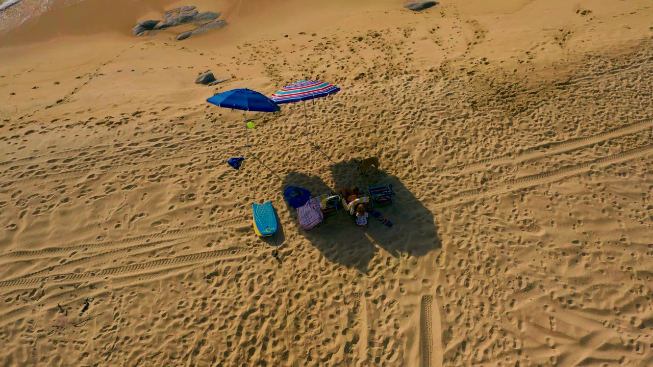 Aerial view of umbrellas and beach gear on open sand