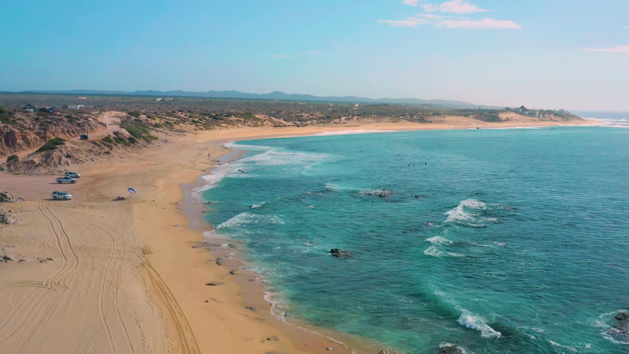 Wide aerial coastline with waves breaking over rocks near shore.