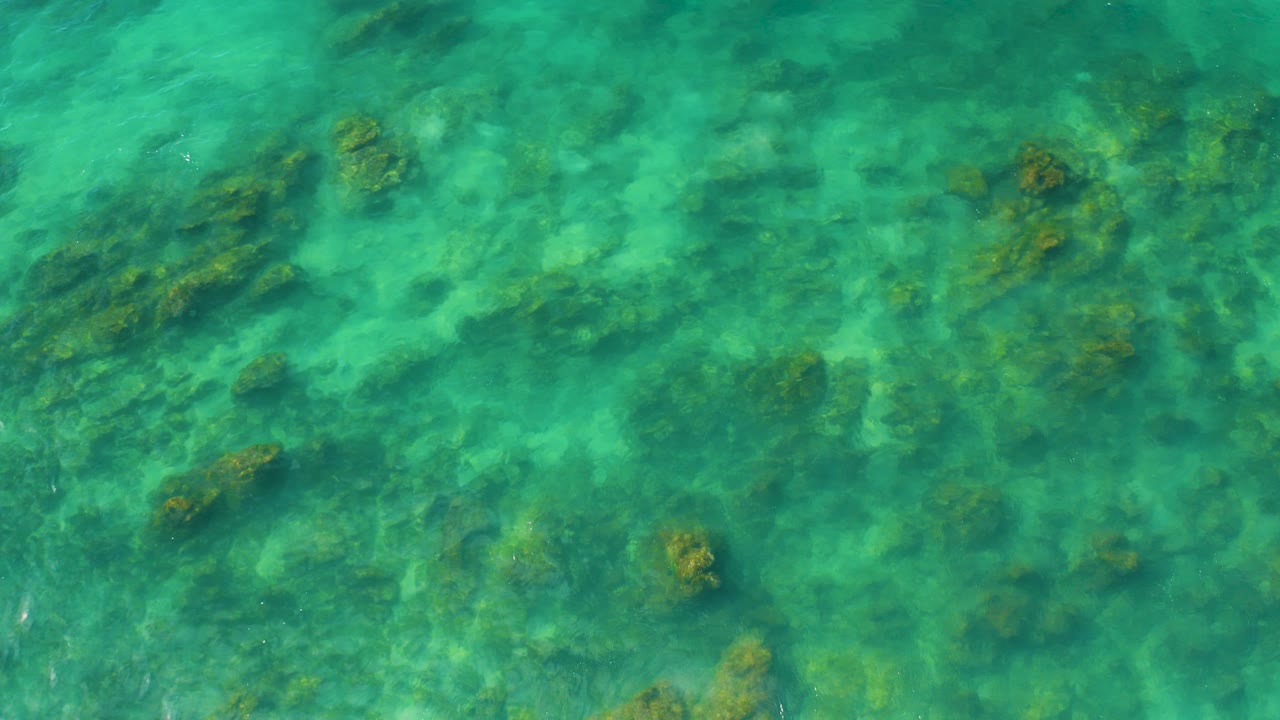 Overhead view of greenish blue water over submerged coral or rock at Shipwrecks Beach, Baja California Sur, with no visible people.