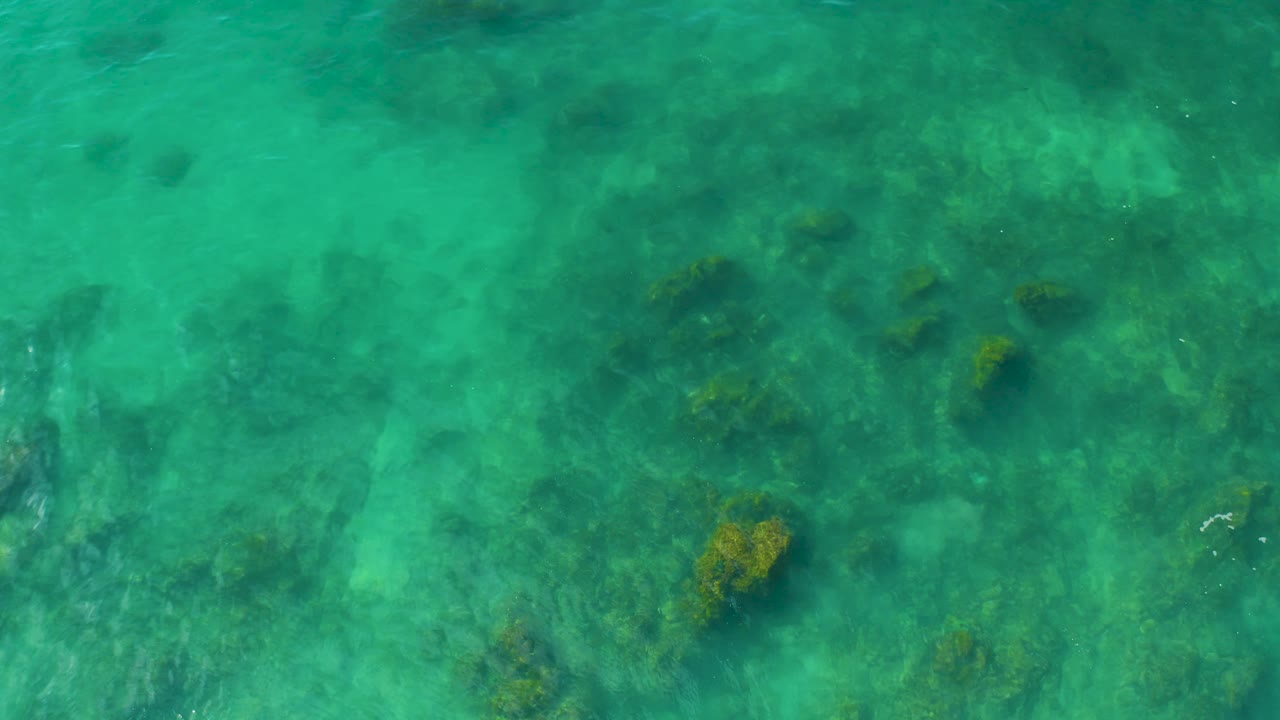 Shallow clear water at Shipwrecks Beach in Baja California Sur covers a broad field of submerged rocks and coral, with no visible people or shoreline.