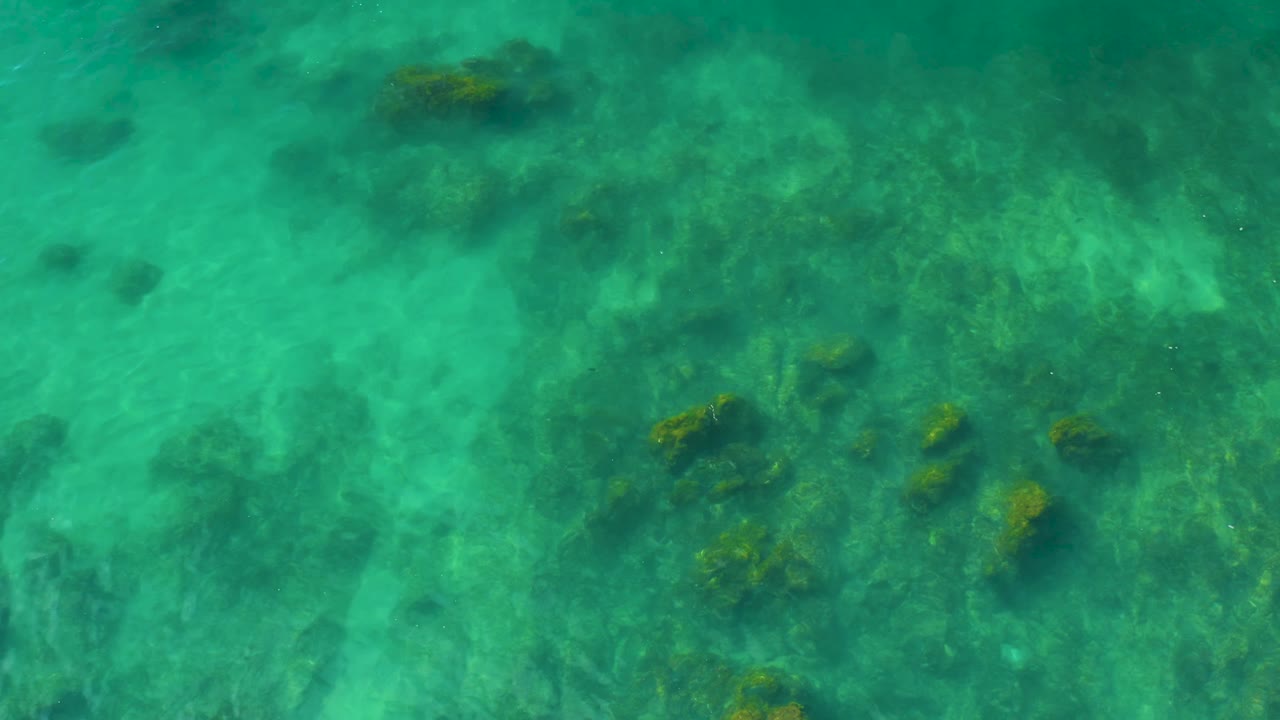 Clear sea with clustered rocks under rippled water.
