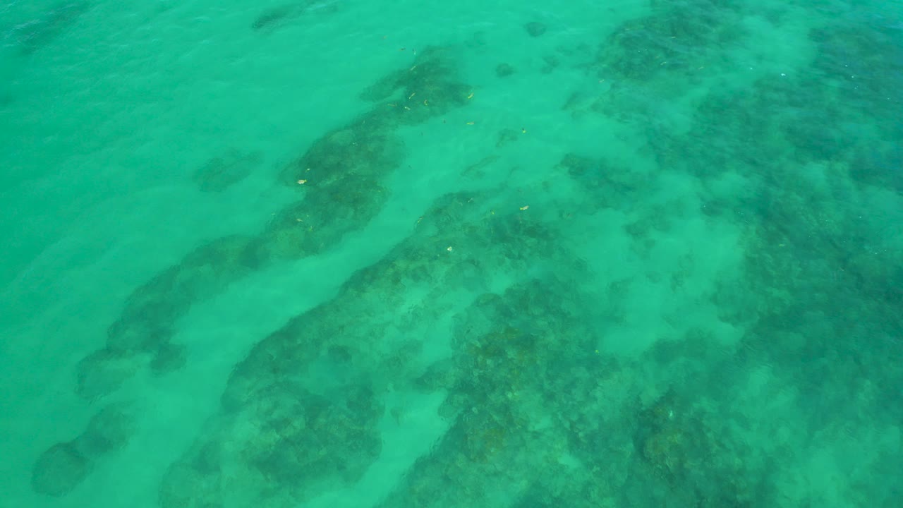 Overhead view of green water and darker submerged reef shapes at Shipwrecks Beach, Baja California Sur, with no visible people.