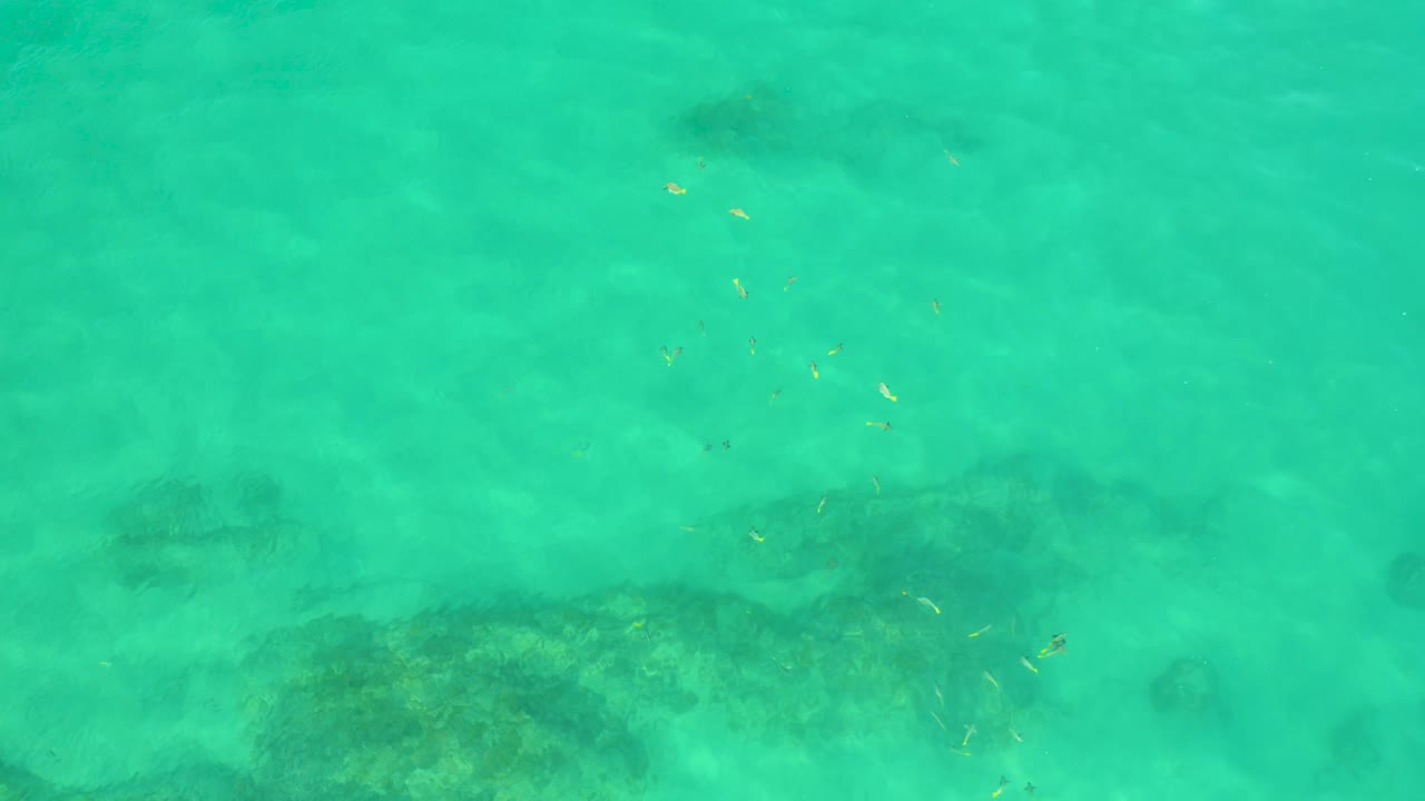 Green-blue water at Shipwrecks Beach, Baja California Sur, covers a broad dark underwater patch near the lower part of the frame, with no visible people.