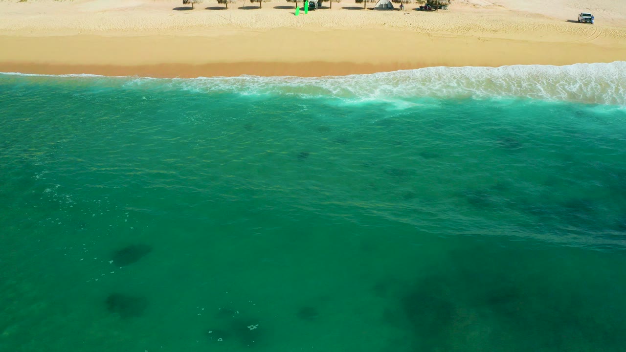 Overhead view of turquoise water meeting a sandy beach.