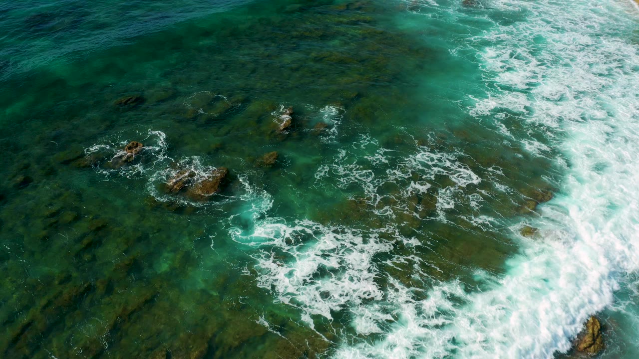 Broad white wave band crossing rocky ocean water