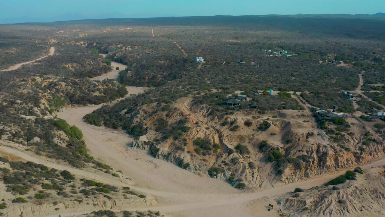 Drone view of eroded desert hills, dirt roads, and open scrubland.