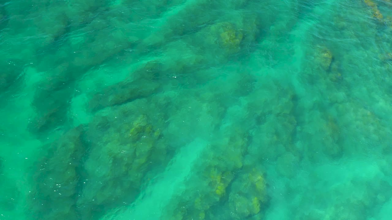 Clear green-blue water crossing underwater rock ledges