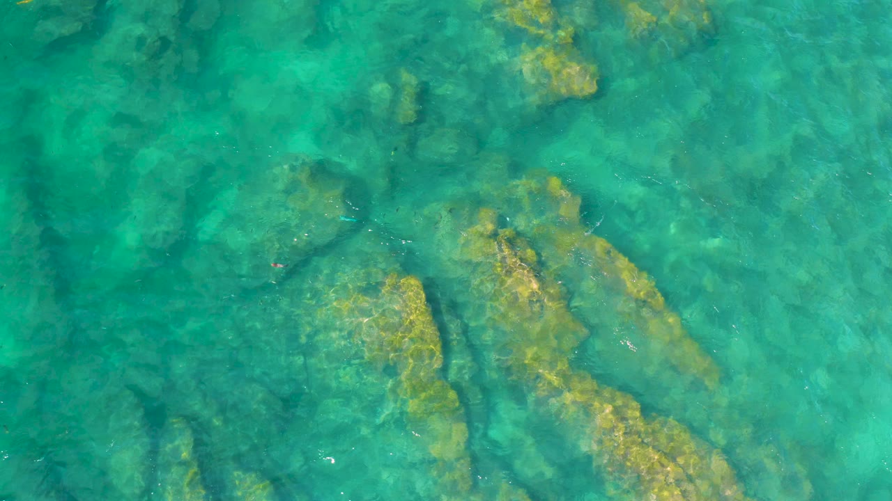 Top-down turquoise ocean with submerged rocks