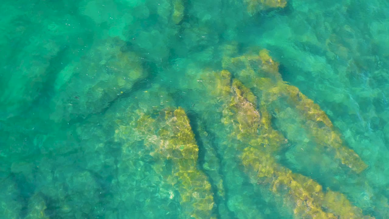 Sunlit underwater rock slabs beneath ripples