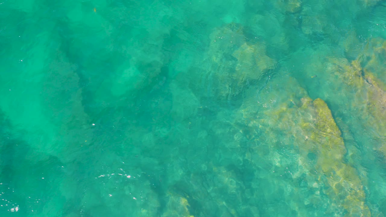 Clear turquoise water ripples above submerged rocks at Shipwrecks Beach, Baja California Sur, with no visible people.