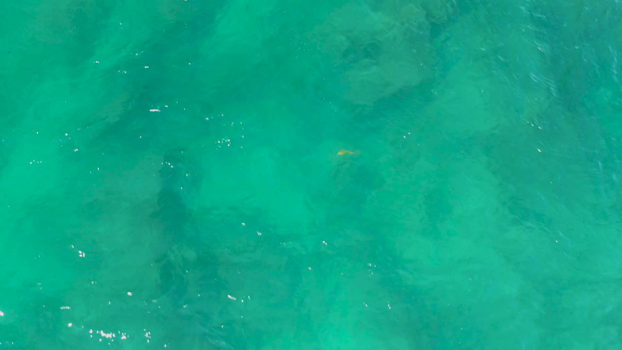 Turquoise sea surface with darker underwater bands.